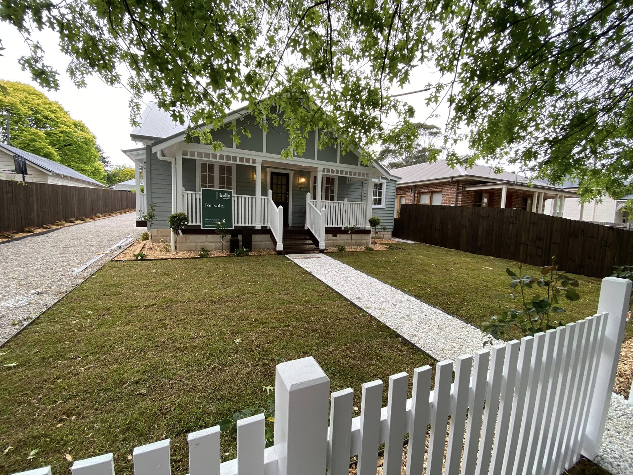 Finished front yard with turf, a white gravel path, planting and picket fence.
